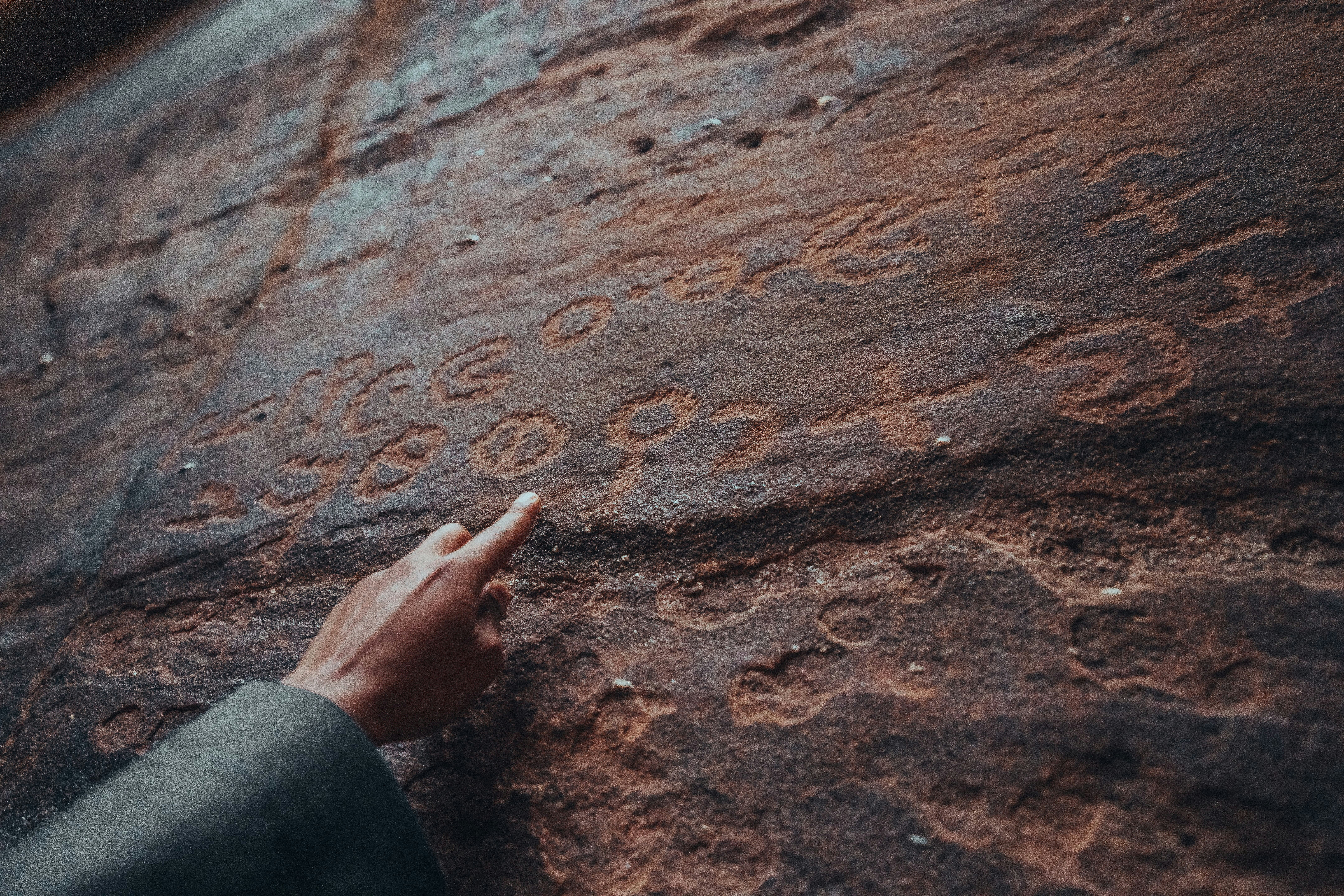 Man pointing to ancient writings in a stone wall